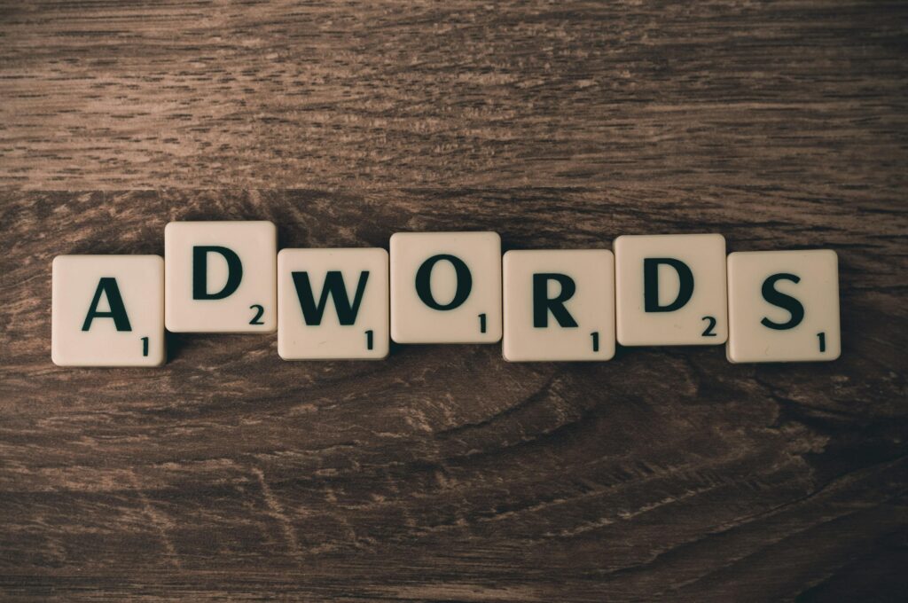Tagline – litery ułożone w słowo ADWORDS na drewnianym tle symbolizujące hasło reklamowe i branding w marketingu internetowym